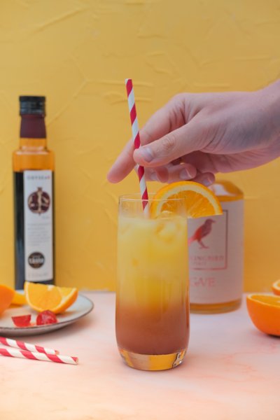 Adding a straw to a tequila sunrise mocktail
