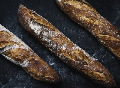 Three crusty French baguettes on a black background dusted with flour