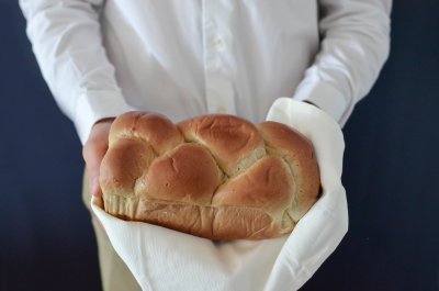 Chef wearing white clothes holding a french brioche
