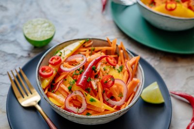 Fresh carrot mango salad served in a beautiful bowl with chilli on top