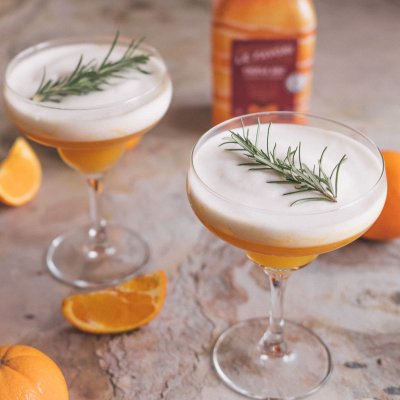 Triple sec cocktail served with vegan foam and rosemary sprigs