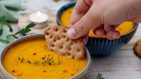Rye biscuit dipped in Nordic pumpkin and orange soup